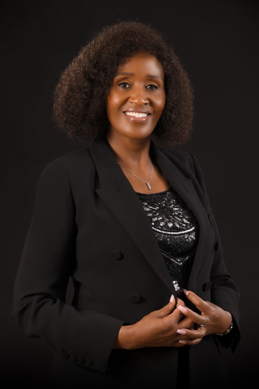 Headshot 2 — black suit, charcoal backdrop, smiling