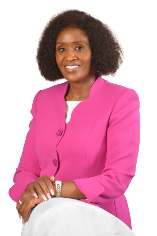 Anne Musau laughing, in a magenta top against a white backdrop