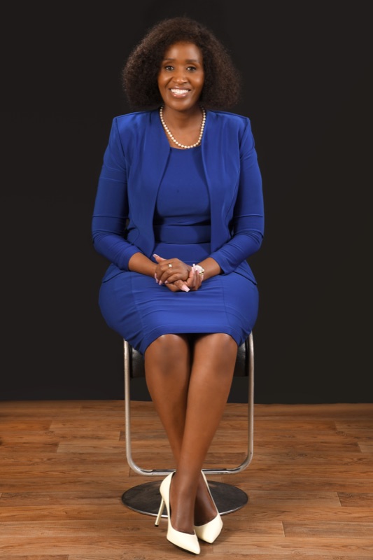 Anne Musau in a royal-blue dress against a white backdrop